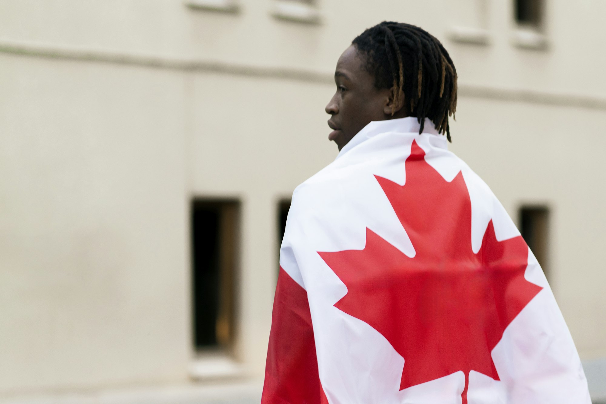 a black male person holding a flag of canada outdoors, concept of patriotism and independence