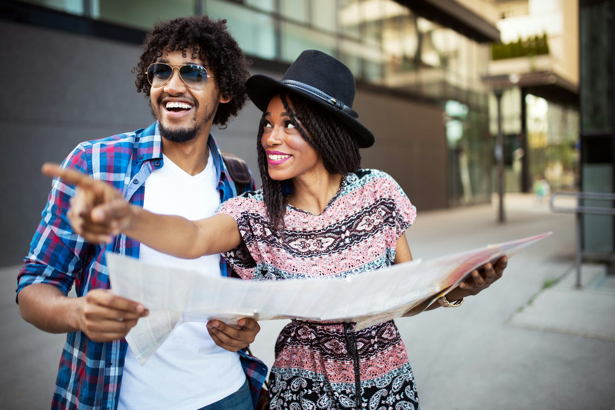 Happy young african couple of travellers holding map in hands